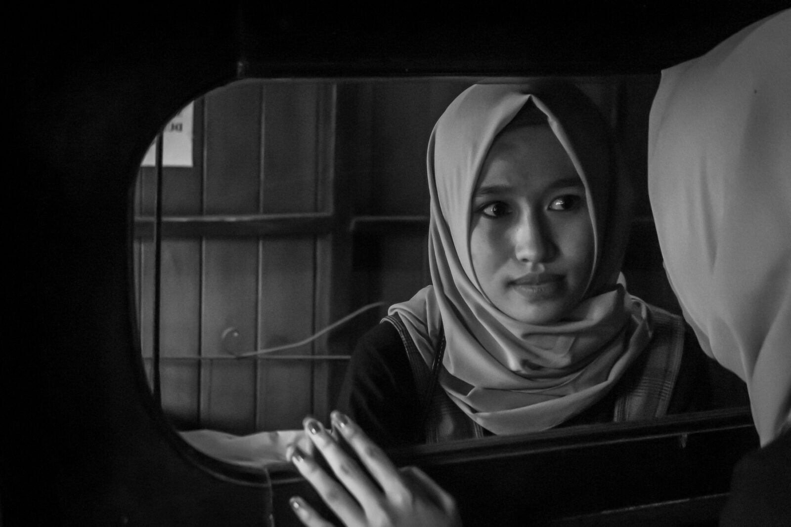 Grayscale Photo of a girl wearing the hijab Looking at a Mirror