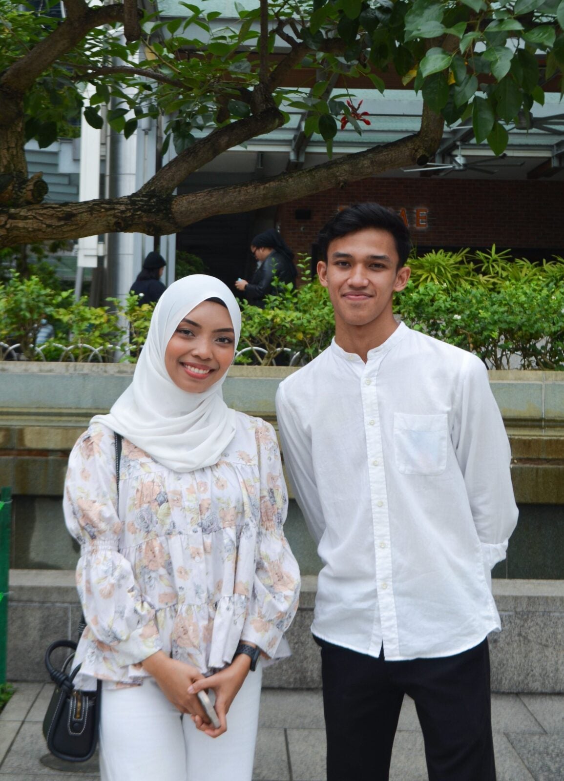 A Malay Couple standing close together and smiling at KLCC park