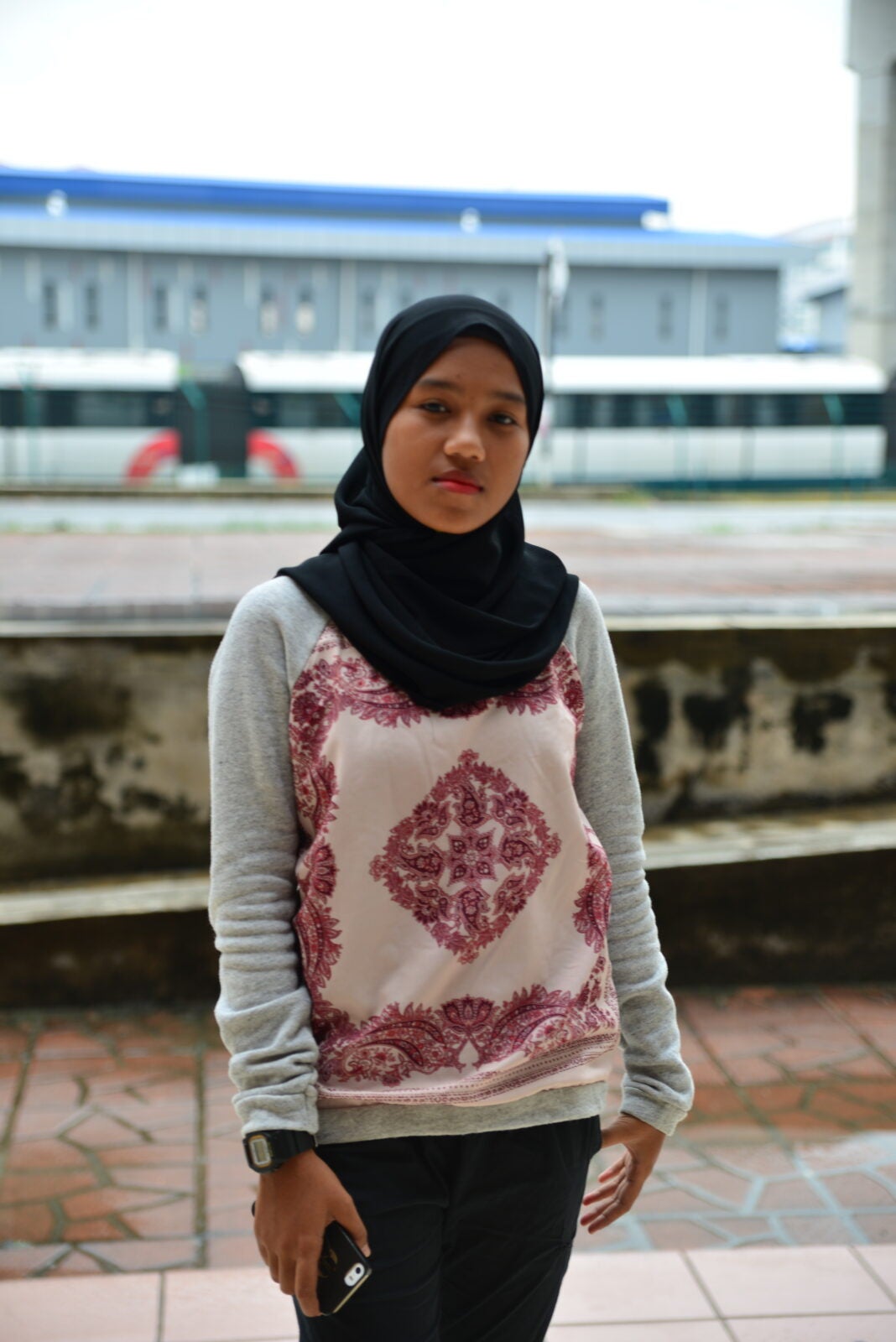 A young Malay girl wearing a shawl and smiling. 