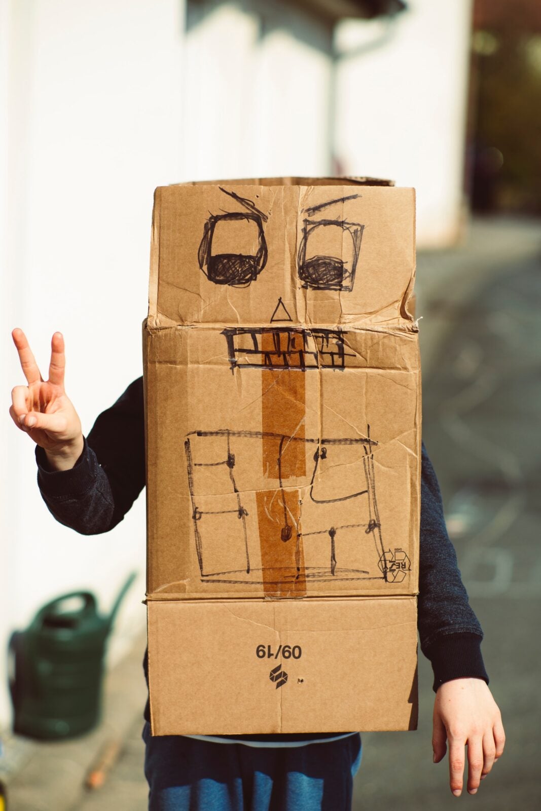 Boy with creative handmade cardboard box roboter simulation.