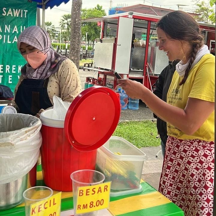 A woman buying food from a street stall in Malaysia. 