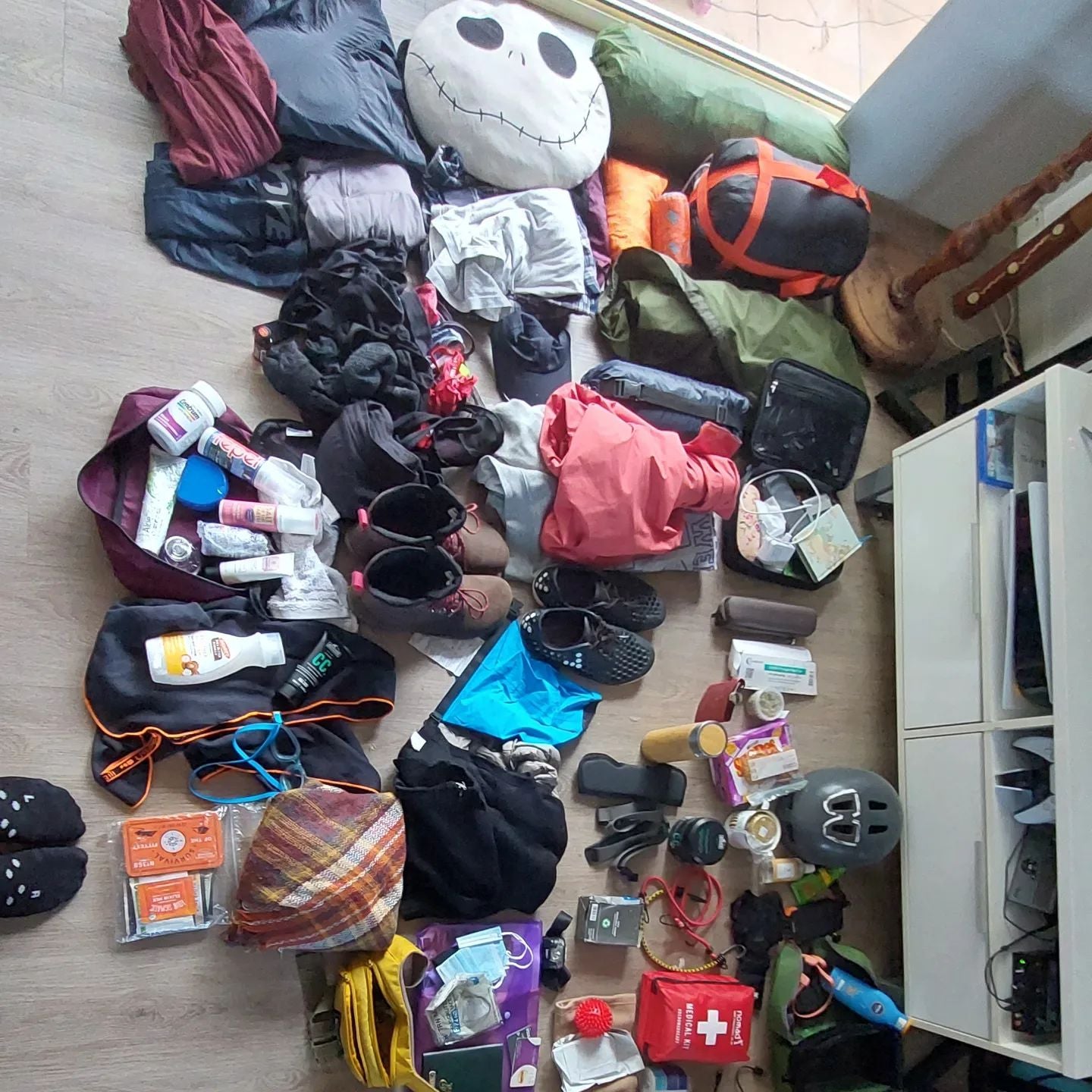 Multiple bags and packed items laid out on a wooden floor.