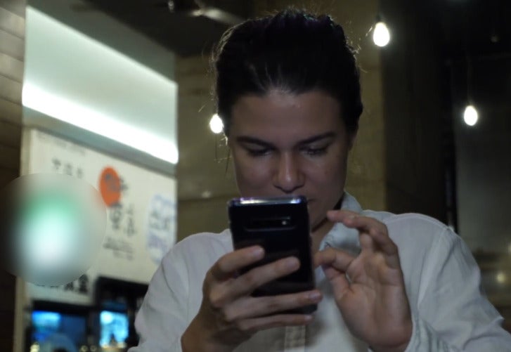 A Swiss Malaysian woman using her phone at a coffee shop.