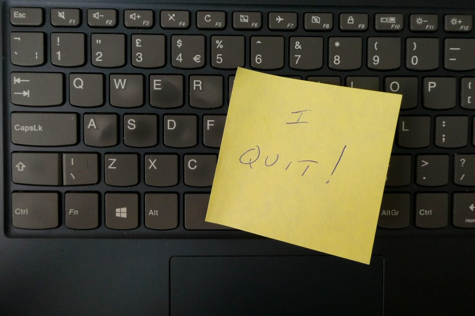 A sticky note pasted on a laptop's keyboard. The note reads: "I quit!"