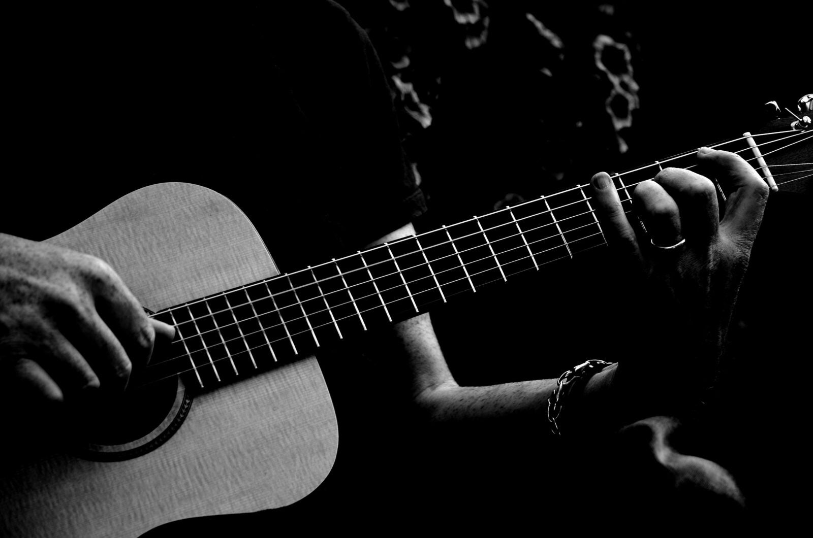 A black and white image. A man playing the guitar