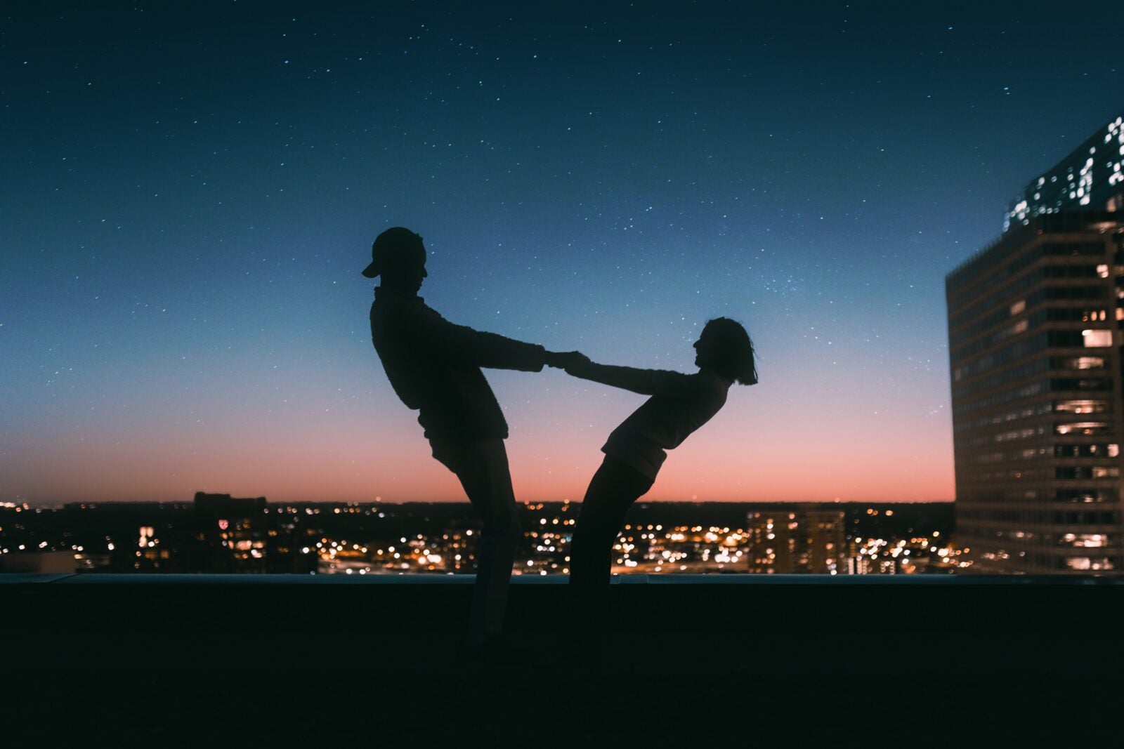 A silhouette of a young couple on a rooftop.