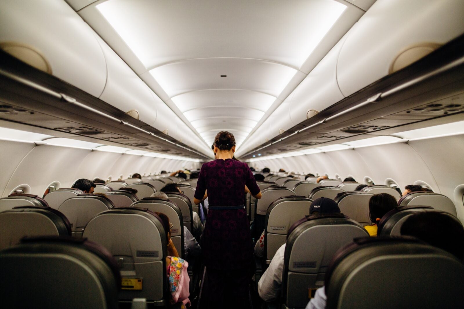 A flight stewardess pushing a trolley through the alley of an airplane