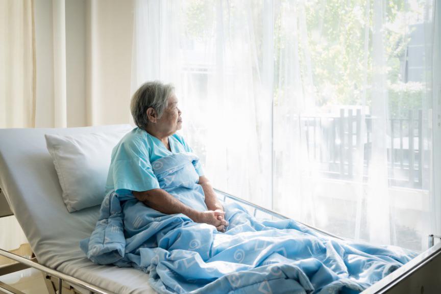 An Elderly Woman Suffering From Alzheimer'S Disease Sitting On A Hospital Bed Looking Out Of The Window