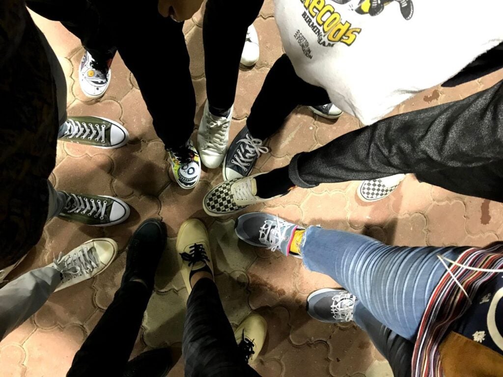 A Picture Of Teenagers Putting Their Feet In A Circle