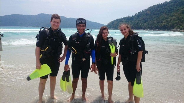 Four divers posing for a photograph on a beach on Perhentian island