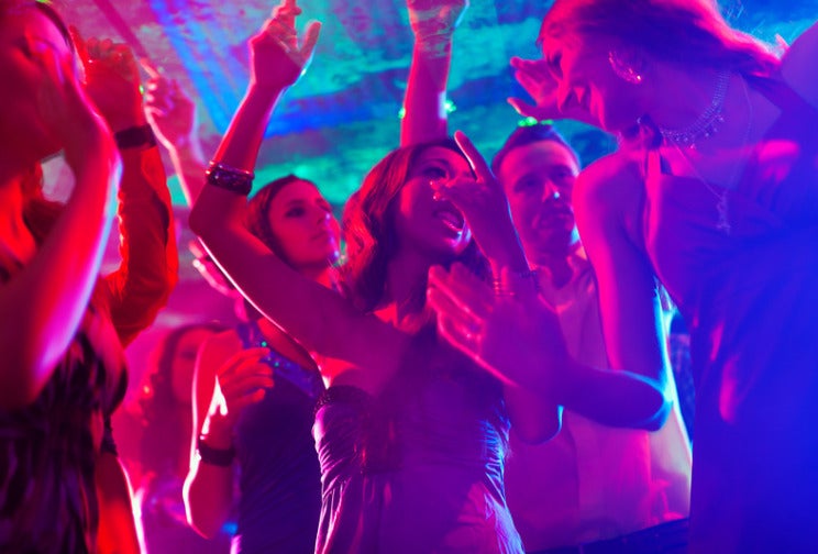 A Woman Dancing At A Party With Her Friends, With Pink And Purple Disco Lighting.