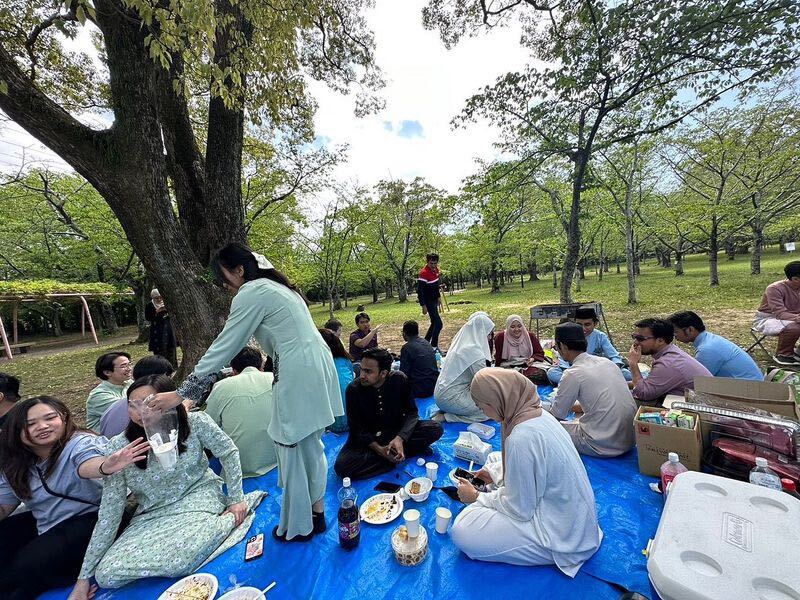Image: People sitting down and having a picnic style lunch.