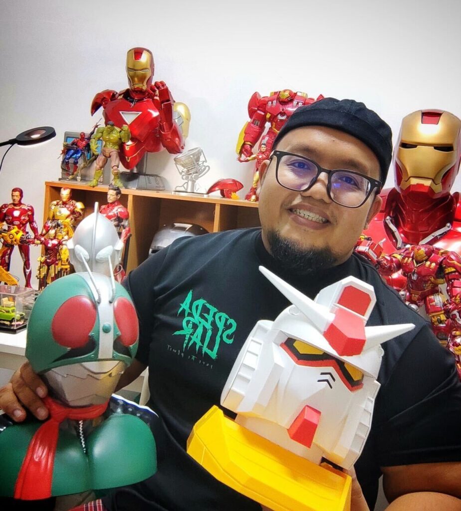Image, Left: Khairulddin Posing With A Gundam And Kamen Rider Bust. Behind Him, His Collection Of Iron Man Suits Are On Display. Image, Right: Khairulddin Puts His Collection Of Special One Piece Sets In A Display Case. 