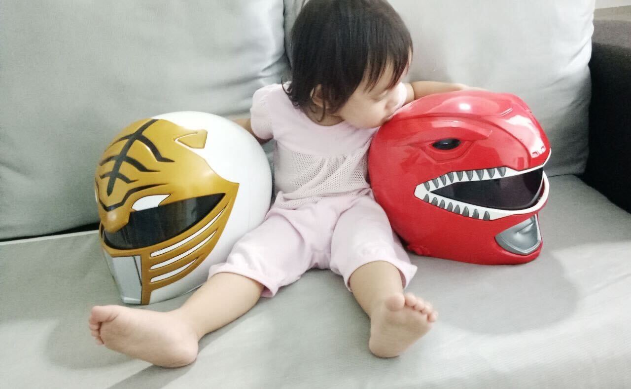 Image: The 2-Year-Old Daughter Of Khairulddin Sitting With His Power Rangers Helmet Collection Featuring The Red And White Rangers, Each Made To A 1:1 Scale. 