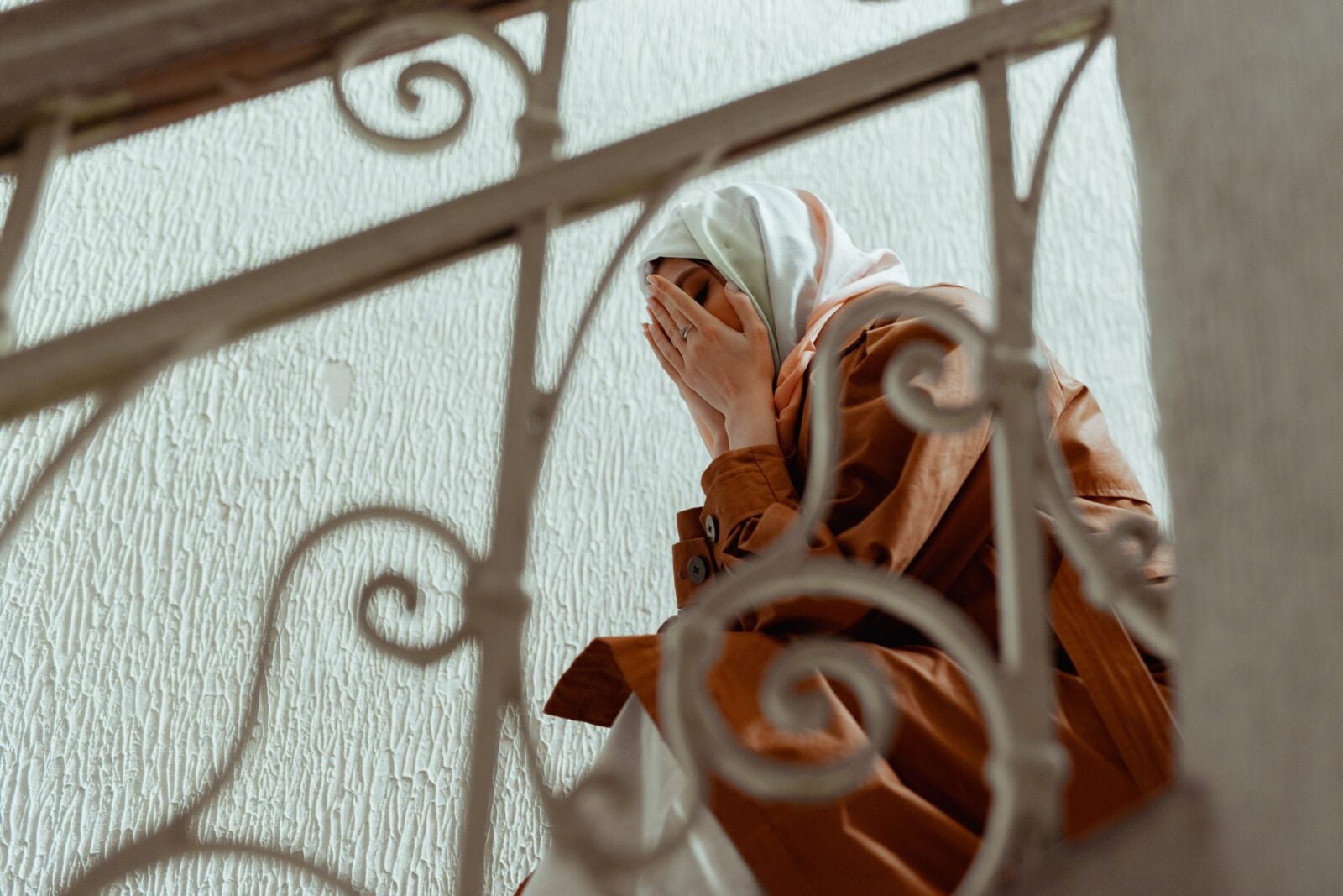 a Muslim woman crying on a flight of stairs