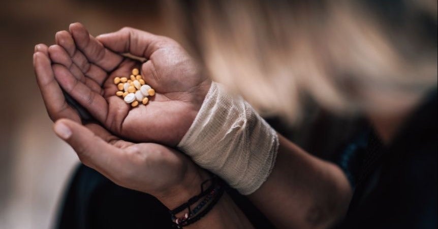 Person Holding Pills With A Bandaged Wrist On Right Arm
