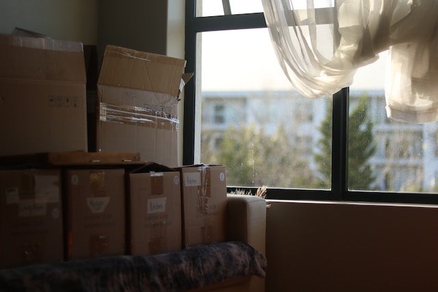 Storage or moving boxes stacked next to a window with morning sun strewing in