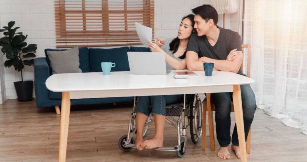 A young woman and a young man sitting at a dining table, both are disabled. Image via Unsplash.